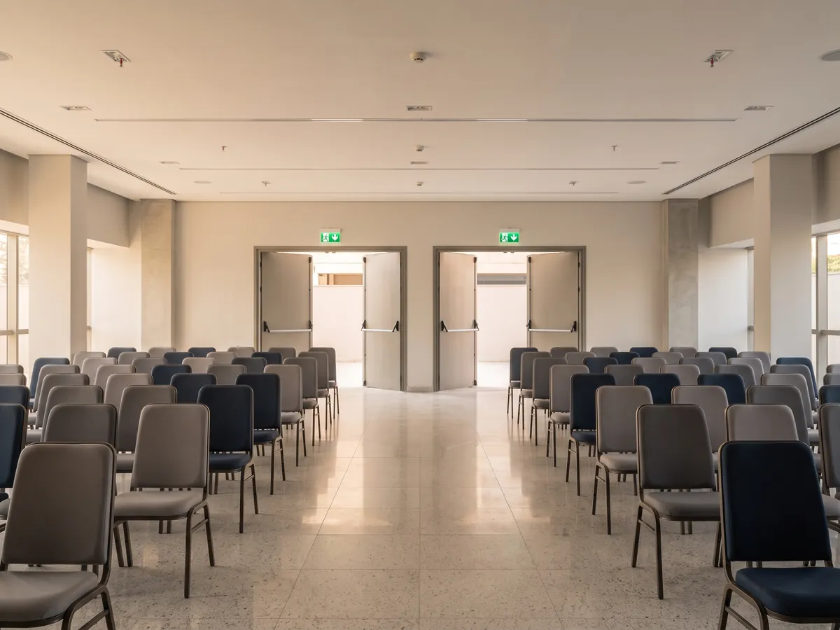 Event hall with rows of chairs and emergency exit doors at the back