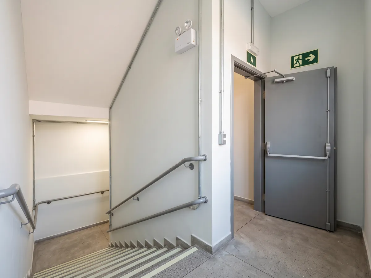 Emergency stairway with a handrail, strips on the steps and a fire door